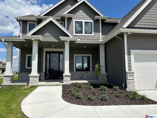 doorway to property with covered porch and a garage