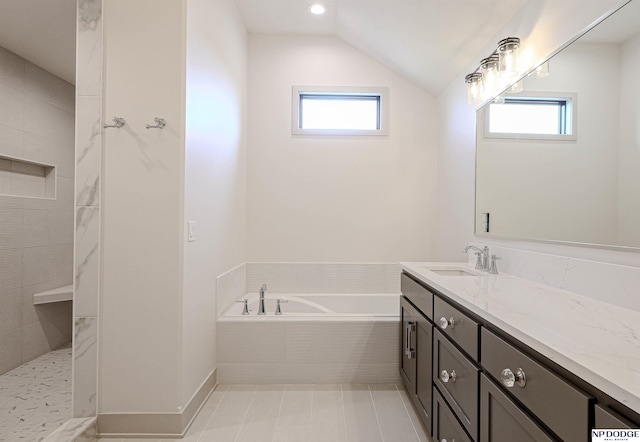 bathroom featuring plenty of natural light, a relaxing tiled tub, lofted ceiling, and vanity