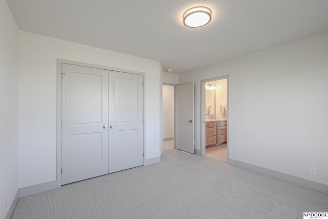 unfurnished bedroom featuring light carpet, connected bathroom, a closet, and sink