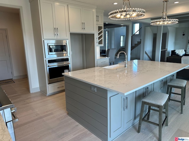 kitchen featuring sink, stainless steel appliances, light stone counters, a spacious island, and pendant lighting