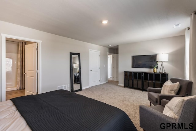 bedroom featuring light carpet and connected bathroom