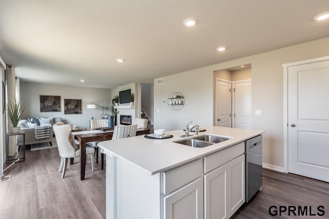 kitchen featuring white cabinetry, a kitchen island with sink, sink, dishwasher, and hardwood / wood-style flooring