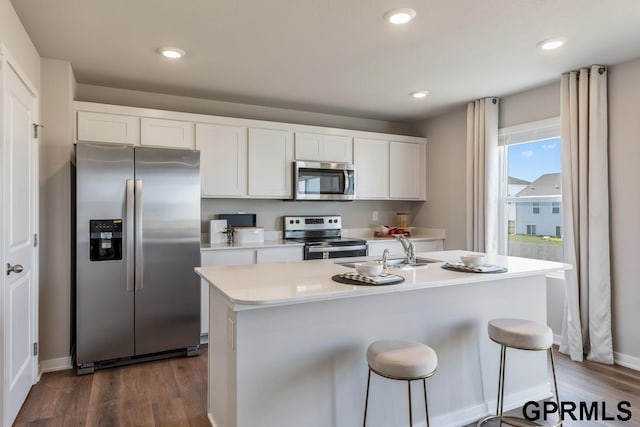 kitchen with a kitchen island with sink, stainless steel appliances, white cabinets, and dark wood-type flooring