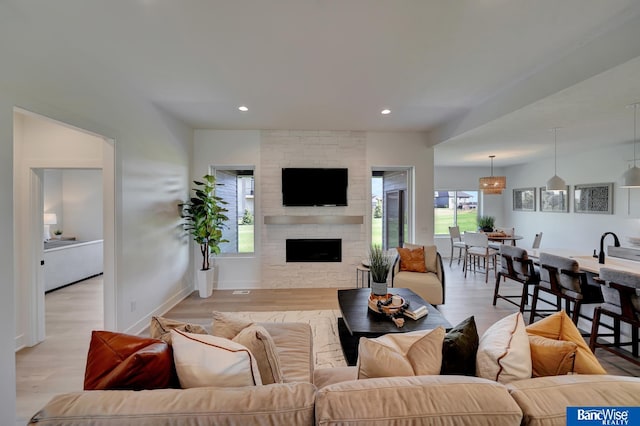 living room featuring a stone fireplace and light wood-type flooring