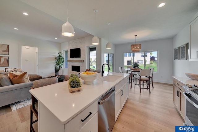 kitchen featuring sink, light hardwood / wood-style flooring, stainless steel appliances, and a kitchen island with sink