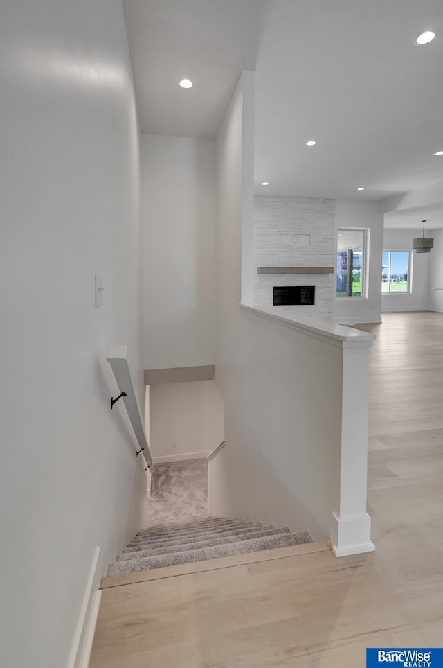 stairway with a fireplace and light hardwood / wood-style floors