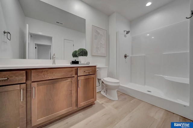 bathroom featuring toilet, a shower, hardwood / wood-style floors, and vanity