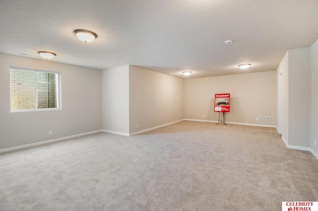 unfurnished room with a textured ceiling and light colored carpet