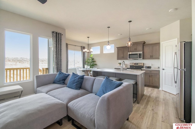 living room with sink, light hardwood / wood-style floors, and an inviting chandelier