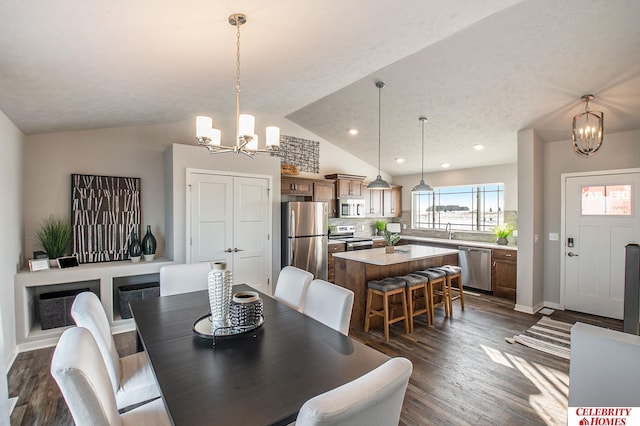 dining room with dark wood-type flooring, a chandelier, sink, vaulted ceiling, and a textured ceiling