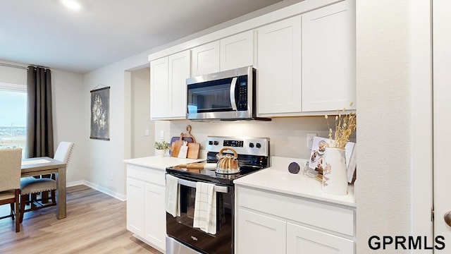 kitchen with white cabinets, light wood-type flooring, and stainless steel appliances