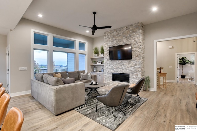 living room with light hardwood / wood-style floors, ceiling fan, and a fireplace