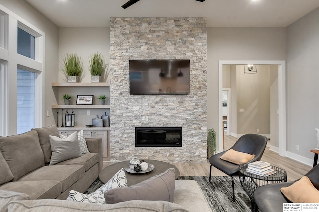 living room with wood-type flooring and a stone fireplace