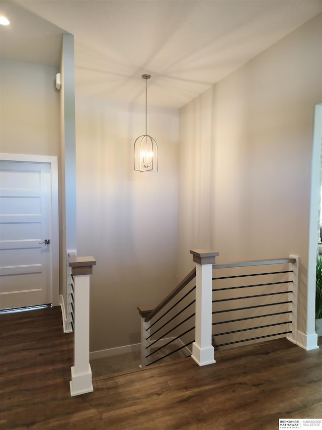 stairs with hardwood / wood-style floors and a notable chandelier