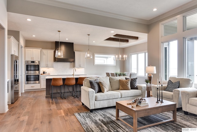 living room featuring ornamental molding, a notable chandelier, hardwood / wood-style flooring, and sink