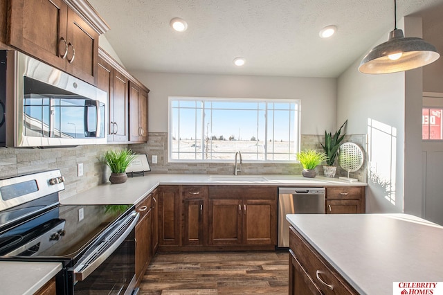 kitchen with decorative light fixtures, stainless steel appliances, tasteful backsplash, sink, and dark hardwood / wood-style flooring