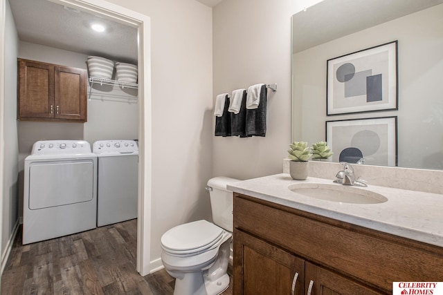 bathroom with wood-type flooring, washing machine and dryer, vanity, and toilet