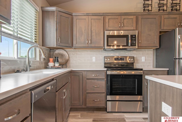 kitchen featuring tasteful backsplash, appliances with stainless steel finishes, sink, and light hardwood / wood-style floors