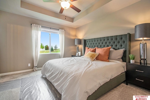 carpeted bedroom with a raised ceiling and ceiling fan