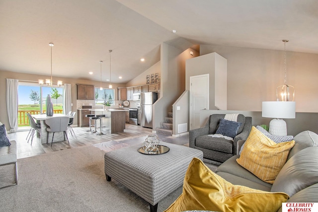 living room with high vaulted ceiling, a notable chandelier, and light hardwood / wood-style floors