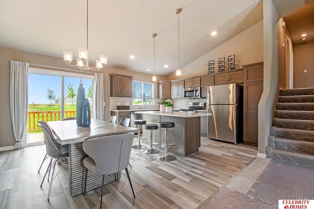 dining space featuring lofted ceiling, sink, a chandelier, and light wood-type flooring