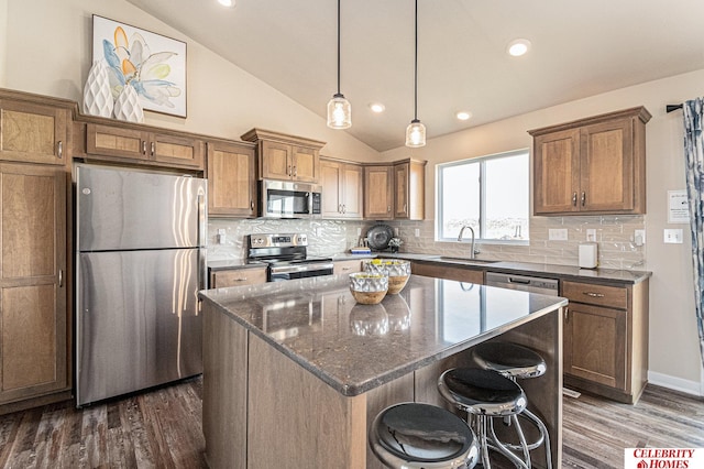 kitchen featuring a kitchen island, dark hardwood / wood-style flooring, lofted ceiling, stainless steel appliances, and a kitchen breakfast bar