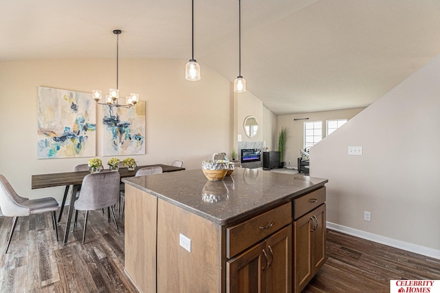 kitchen with vaulted ceiling, dark stone countertops, dark hardwood / wood-style flooring, a center island, and a chandelier