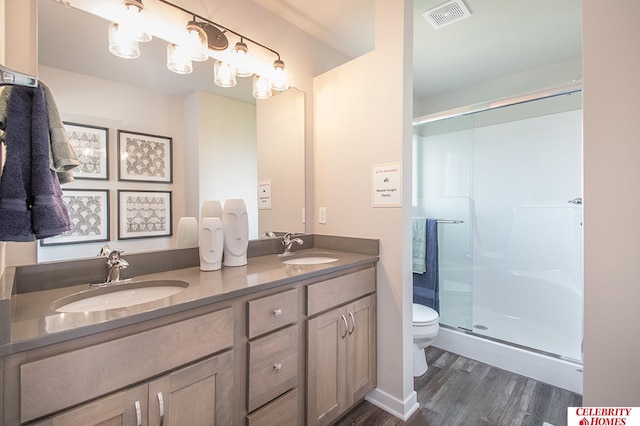 bathroom with large vanity, toilet, an enclosed shower, hardwood / wood-style flooring, and dual sinks