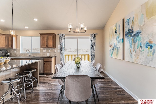 dining room with sink, a chandelier, vaulted ceiling, and dark wood-type flooring