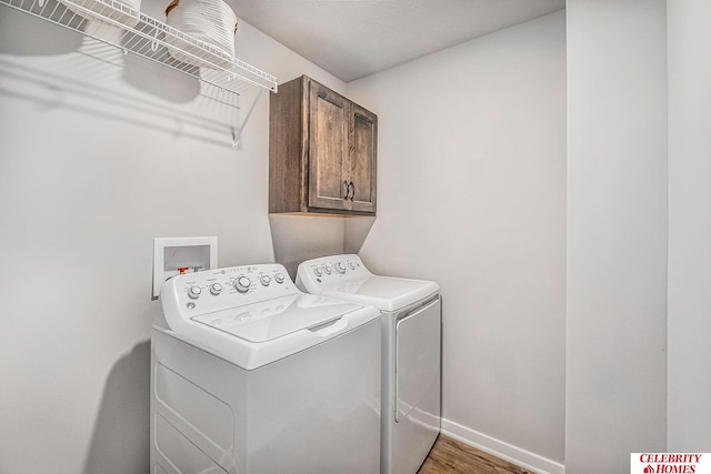 clothes washing area featuring hardwood / wood-style floors, cabinets, washer hookup, and washing machine and clothes dryer