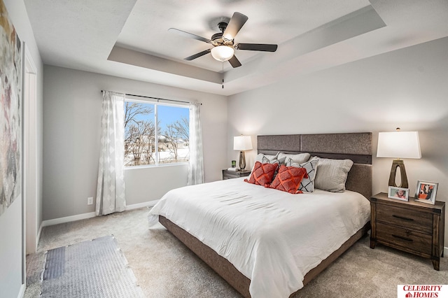 bedroom with a raised ceiling, light carpet, and ceiling fan