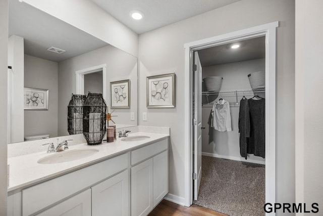 bathroom featuring wood-type flooring, oversized vanity, toilet, and double sink