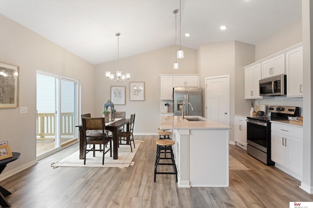 kitchen with decorative light fixtures, appliances with stainless steel finishes, white cabinetry, sink, and light wood-type flooring