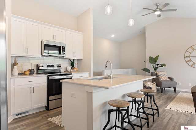 kitchen with a kitchen island with sink, decorative light fixtures, hardwood / wood-style floors, stainless steel appliances, and tasteful backsplash