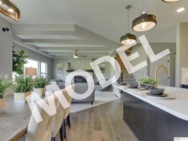 dining area with wood-type flooring, ceiling fan, and beam ceiling