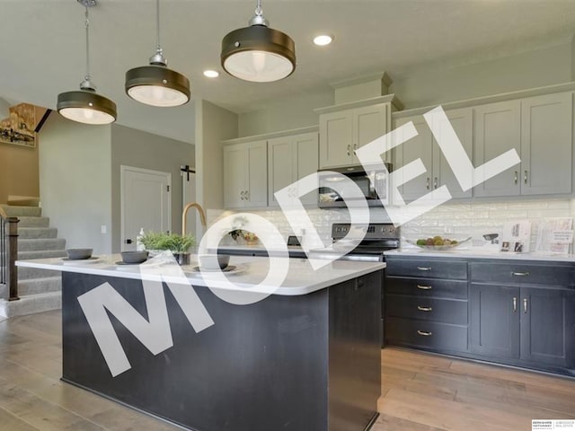 kitchen with white cabinets, backsplash, hanging light fixtures, light hardwood / wood-style flooring, and a kitchen island with sink