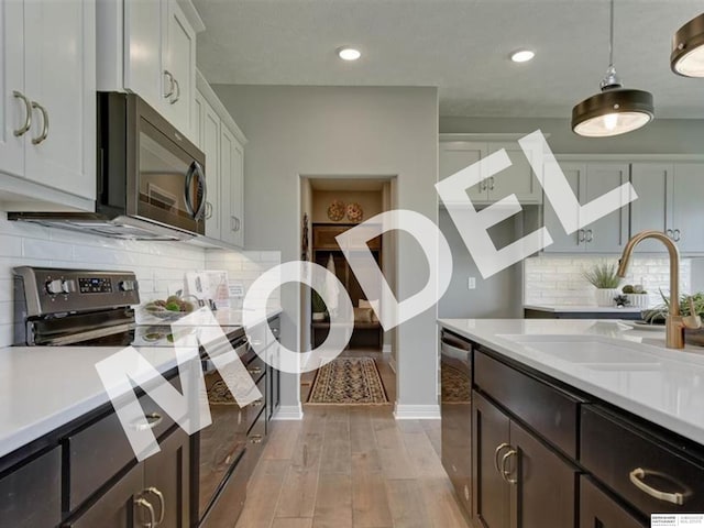 kitchen with hanging light fixtures, stainless steel appliances, light hardwood / wood-style floors, tasteful backsplash, and sink