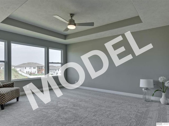 living area with a tray ceiling and carpet flooring