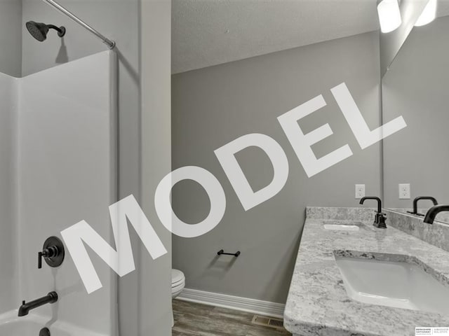 full bathroom featuring a textured ceiling, bathtub / shower combination, toilet, wood-type flooring, and dual bowl vanity