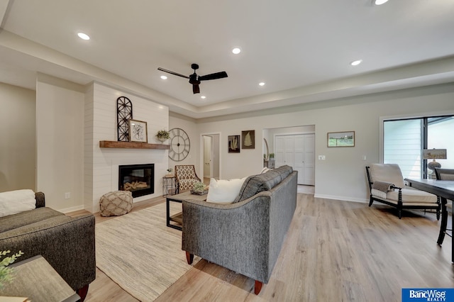 living room with light hardwood / wood-style flooring, a fireplace, ceiling fan, and brick wall