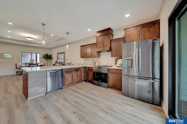 kitchen with appliances with stainless steel finishes, kitchen peninsula, and light hardwood / wood-style flooring