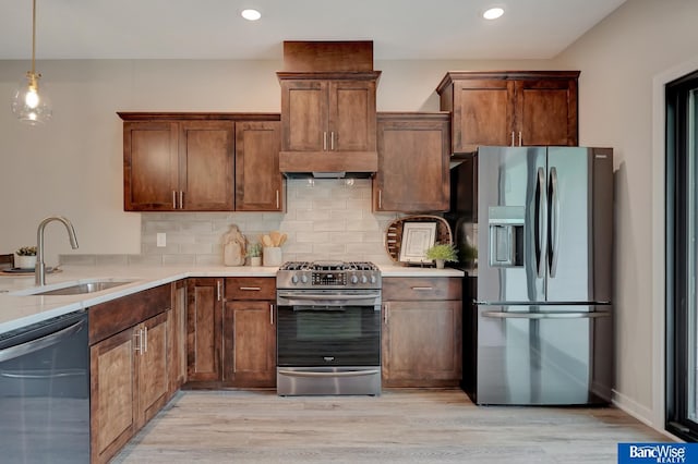 kitchen with sink, appliances with stainless steel finishes, backsplash, and light wood-type flooring