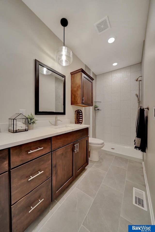 bathroom featuring tiled shower, toilet, tile floors, and vanity