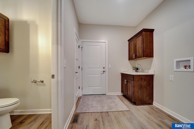 washroom with washer hookup, sink, and light wood-type flooring