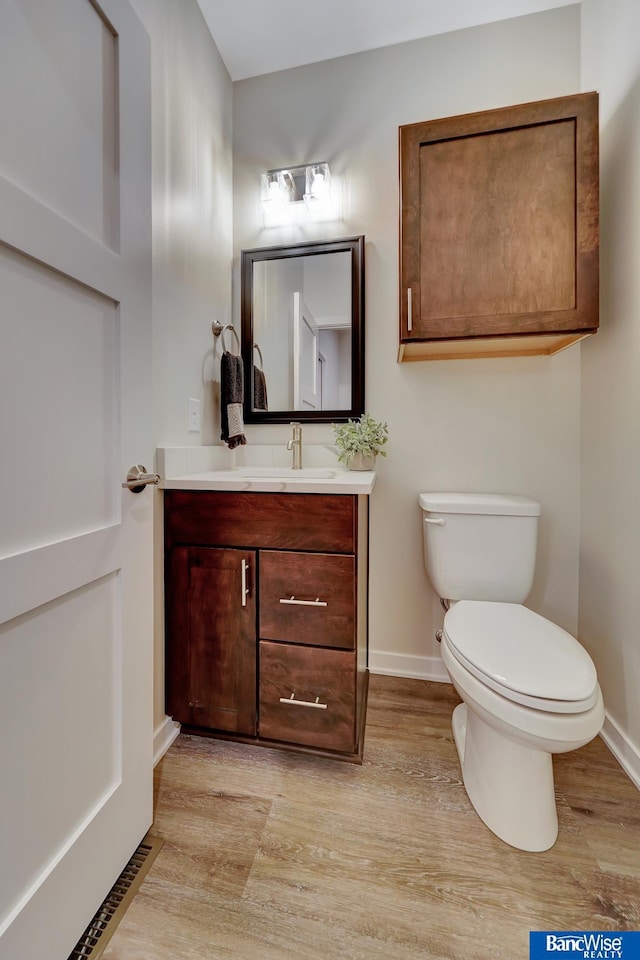 bathroom with hardwood / wood-style floors, vanity, and toilet