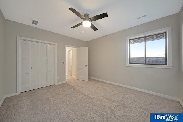 unfurnished bedroom with light colored carpet, ceiling fan, and a closet