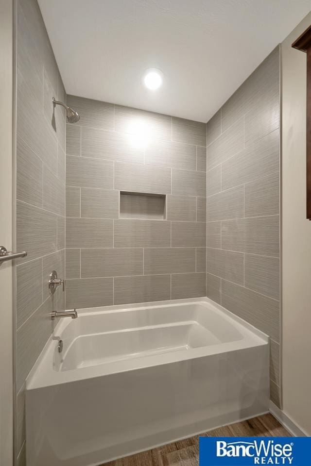 bathroom with hardwood / wood-style flooring and tiled shower / bath