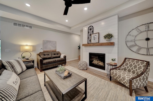 living room with light hardwood / wood-style floors, ceiling fan, and a fireplace