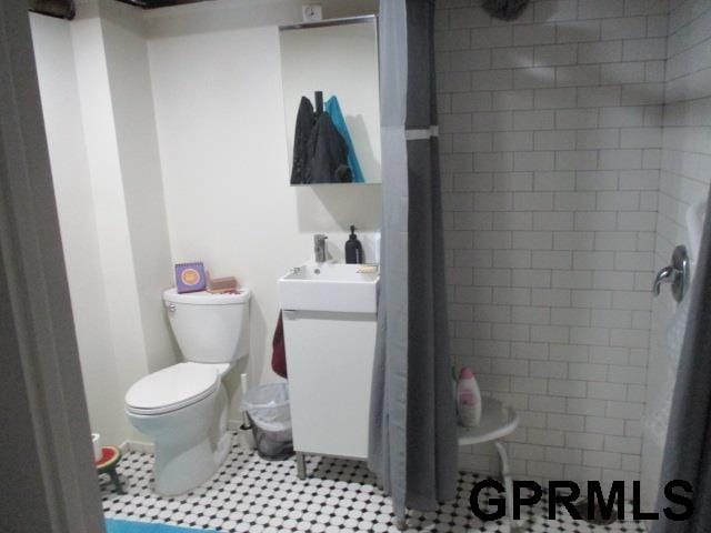 bathroom with tile floors, a tile shower, vanity, and toilet