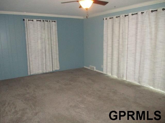 unfurnished room featuring crown molding, ceiling fan, and carpet floors